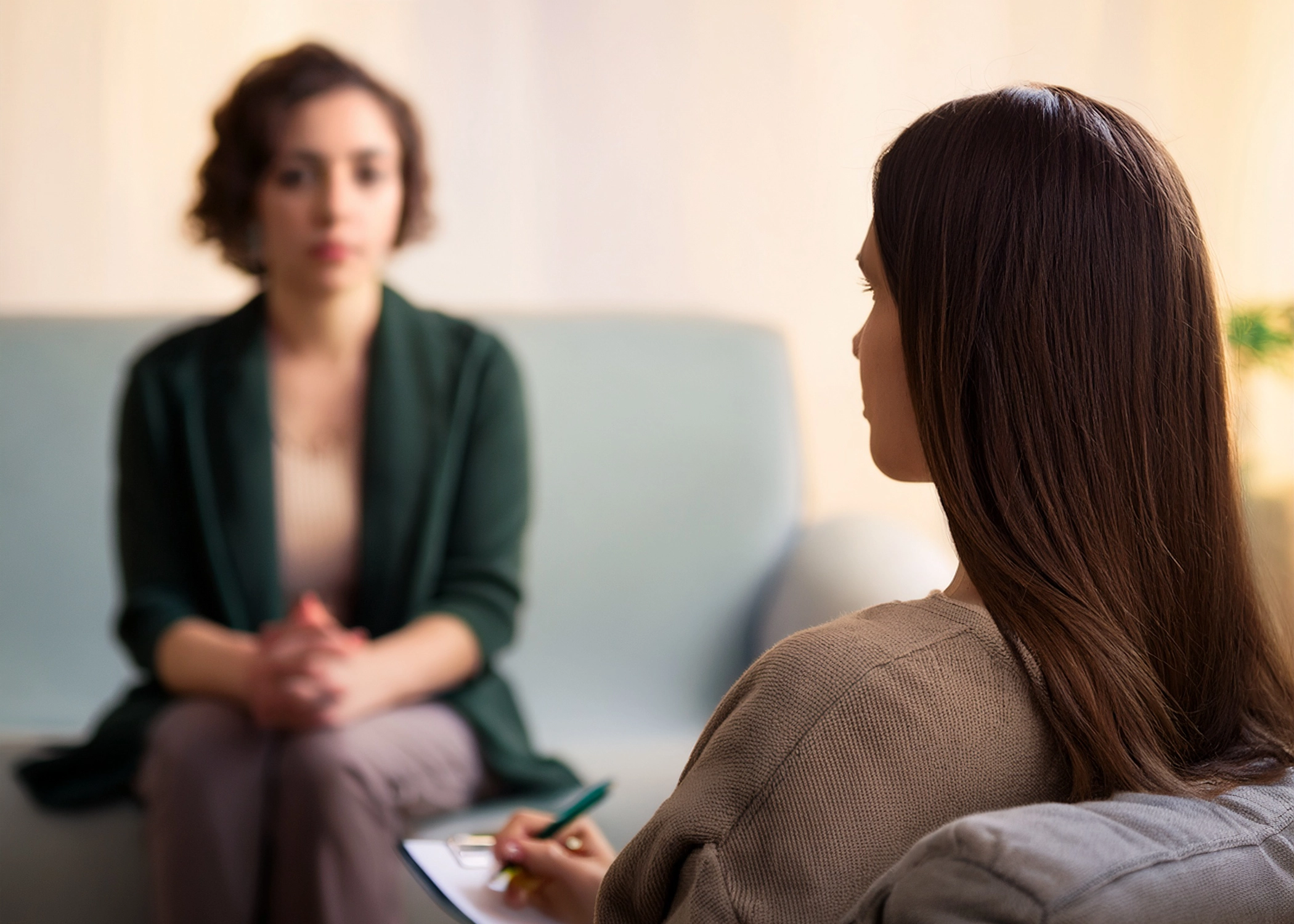 Two women sitting face to face during a therapy in Portuguese session