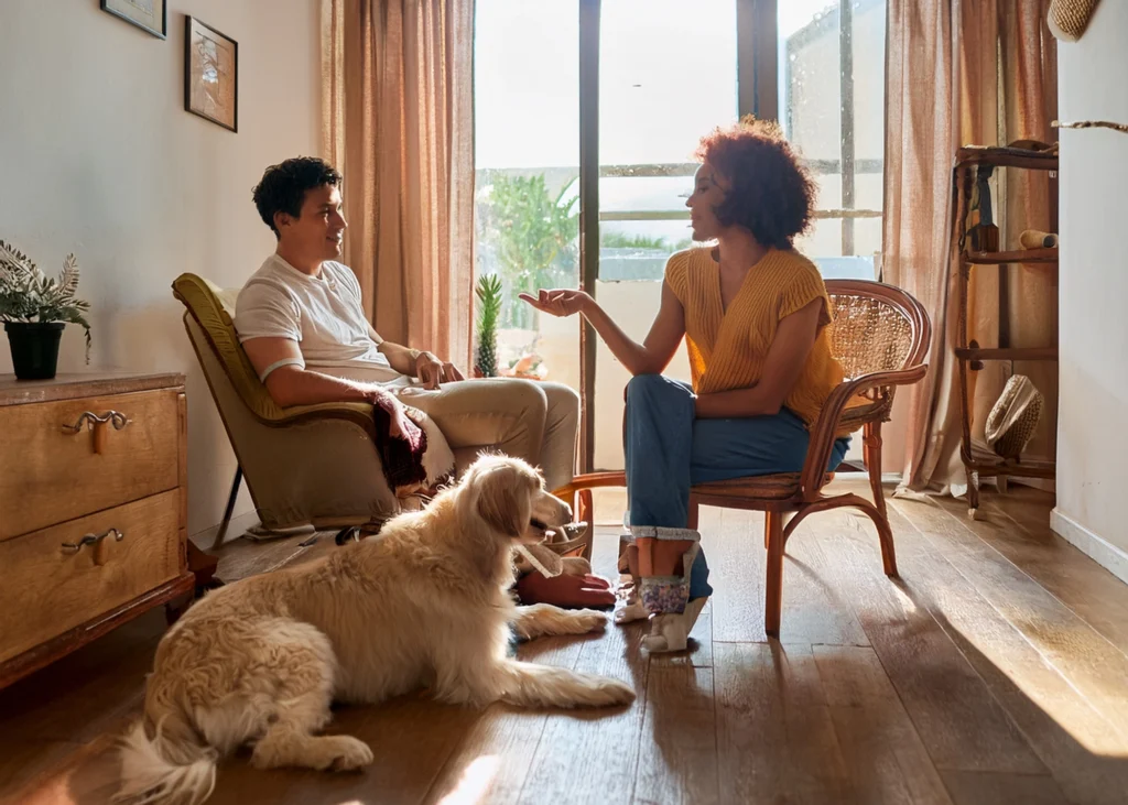 Couple sitting in a living room with their dog, reflecting the couples' emotional dynamics.